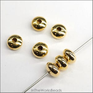 May include: Gold-coloured metal beads with a hole in the centre. The beads are round and flat, and they are strung on a wire.