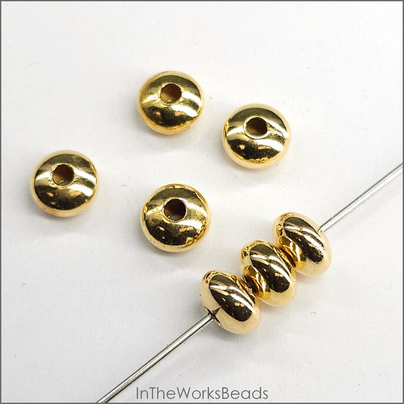 May include: Gold-coloured metal beads with a hole in the centre. The beads are round and flat, and they are strung on a wire.