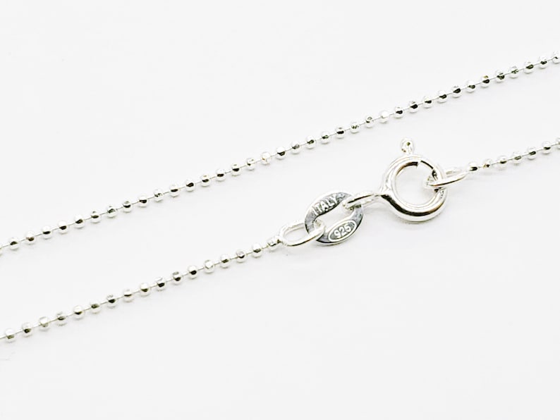 Puede incluir: Un collar de cadena de plata con estilo de cadena de bolas. La cadena tiene un cierre de langosta y una etiqueta que dice "ITALY 925".