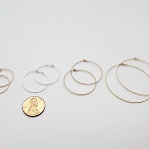 May include: Four pairs of hoop earrings in different sizes. The earrings are made of silver and gold metal and have a textured finish.