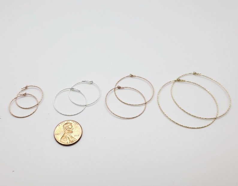 May include: Four pairs of hoop earrings in different sizes. The earrings are made of silver and gold metal and have a textured finish.
