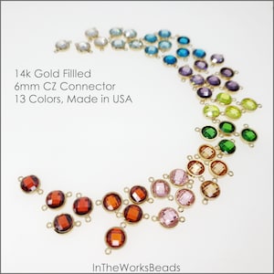 May include: 14k gold filled 6mm CZ connectors in 13 colors. The connectors are round with two loops on each side. The colors are arranged in a rainbow pattern.
