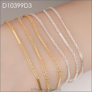 May include: Close-up of multiple delicate chain necklaces in gold and silver. The chains feature various designs, including textured bars and classic link styles. The image includes the text "D10399D3" and "InTheWorksBeads".