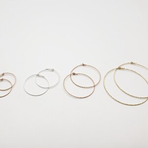 May include: Five pairs of hoop earrings in different sizes. The earrings are made of silver, gold, and rose gold. The hoops are all textured.
