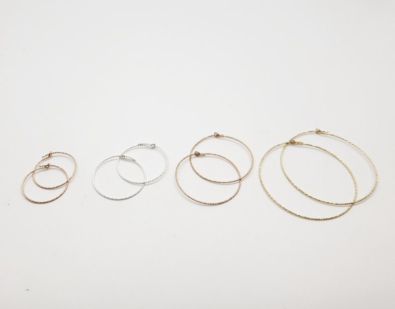 May include: Five pairs of hoop earrings in different sizes. The earrings are made of silver, gold, and rose gold. The hoops are all textured.