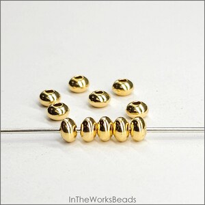 May include: A close-up of a strand of gold-coloured beads, with additional beads scattered around. The beads are round and have a smooth, shiny finish.