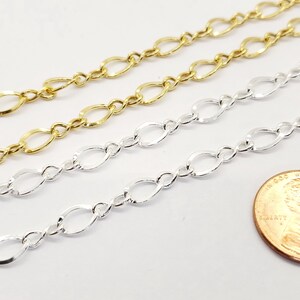 May include: Close-up of gold and silver oval link chains. The chains are displayed diagonally. A penny is included for size comparison. The chains are likely for jewellery making.
