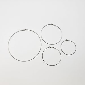 May include: Three silver hoop earrings of different sizes. The largest hoop is about 2 inches in diameter, the middle hoop is about 1.5 inches in diameter, and the smallest hoop is about 1 inch in diameter.