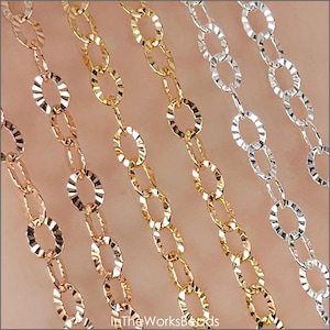 May include: Close-up of several delicate chains in gold, rose gold, and silver. Each chain features a repeating pattern of textured, oval-shaped links. The chains are displayed diagonally, showcasing their intricate design and metallic sheen.