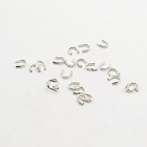 Op de afbeelding: Een groep zilverkleurige metalen krimpkralen, gebruikt voor het maken van sieraden.