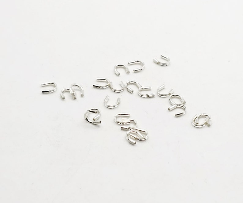 Op de afbeelding: Een groep zilverkleurige metalen krimpkralen, gebruikt voor het maken van sieraden.