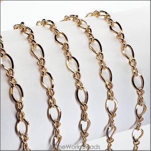 14k gold filled figure 8 flat curb chain draped on bracelet bar. Features 5.5mm x 8.6mm oval links and 3mm x 8.5mm figure 8 connectors. Constructed with 19 gauge wire.