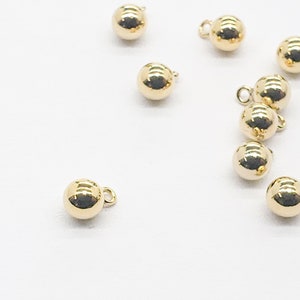 May include: A group of ten gold-colored round buttons with a small loop on each button.
