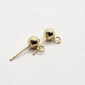 May include: Two gold-toned earring findings with a round ball at the top and a loop at the bottom.