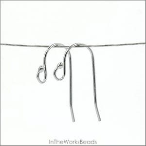 May include: Two silver earring hooks with a small loop at the top and a long, thin wire extending down. The hooks are hanging from a thin wire.
