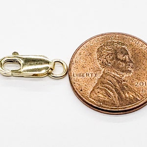 Puede incluir: Cierre de langosta dorado para la elaboraci&oacute;n de joyas, mostrado junto a un centavo de d&oacute;lar estadounidense para comparar el tama&ntilde;o.