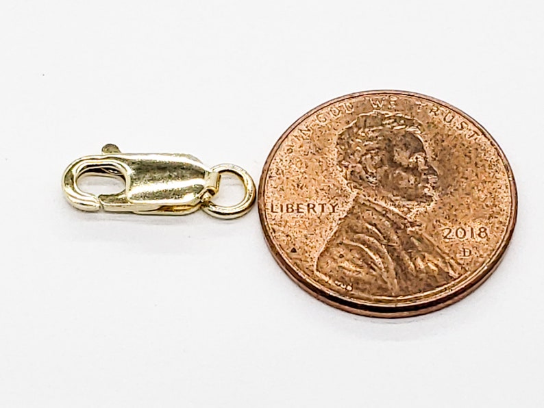 Puede incluir: Cierre de langosta dorado para la elaboraci&oacute;n de joyas, mostrado junto a un centavo de d&oacute;lar estadounidense para comparar el tama&ntilde;o.