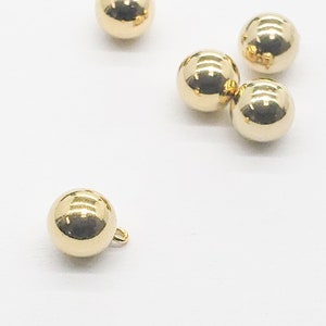 May include: Five gold-colored round buttons, one with a small loop on the side.
