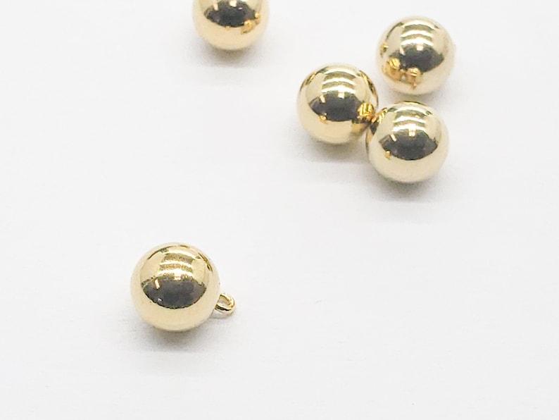 May include: Five gold-colored round buttons, one with a small loop on the side.