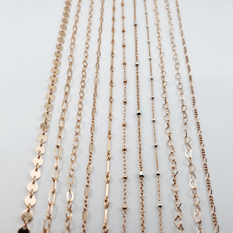 May include: A collection of 10 gold chains with different styles and lengths. The chains are arranged in a row on a white background.