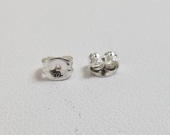 May include: Two silver earring backs, one with a post and the other with a flat back marked with the number "92".