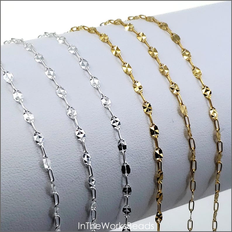 May include: Four silver and gold chain necklaces with a diamond-shaped pattern. The chains are displayed on a white surface. InTheWorksBeads is printed on the surface.