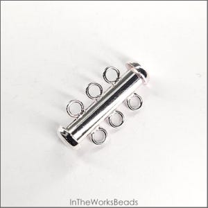 May include: Silver-toned metal four-strand connector clasp for jewelry making. The clasp has four loops on each side and a cylindrical shape.