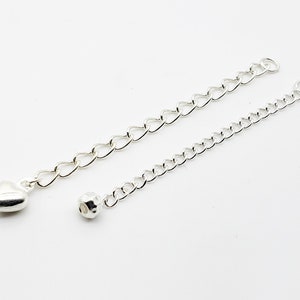 May include: Two silver chains with a heart charm and a bead on one end. The chains are approximately 10 inches long.