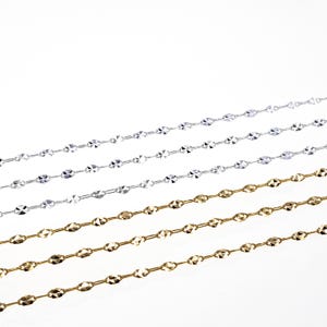 May include: Four chains, two silver and two gold, with a diamond-cut pattern. The chains are laid out in a diagonal pattern on a white background.