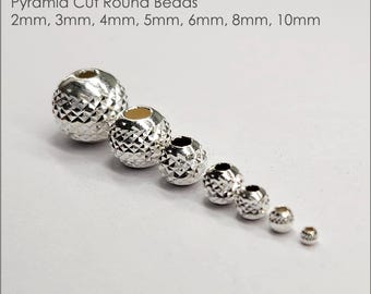 May include: A set of seven silver pyramid cut round beads in various sizes, ranging from 2mm to 10mm. The beads are arranged in order of size, with the largest bead on the left and the smallest bead on the right. The beads are made of .925 sterling silver.