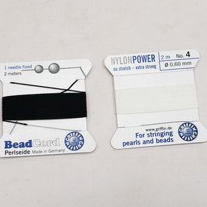 May include: Two spools of beading thread. The spool on the left is black and says "Bead Cord Periseide Made in Germany". The spool on the right is white and says "NYLONPOWER 2 m No. 4 0,60 mm no stretch - extra strong www.griffin.de For stringing pearls and beads".