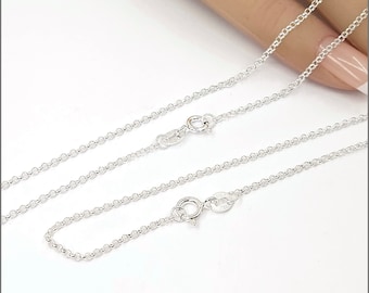 May include: Two silver chains with lobster claw clasps. The chains are laid out on a white surface.