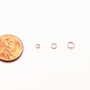 May include: Three small gold jump rings, each with a different diameter, are shown next to a US penny for size comparison.