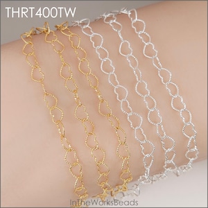 May include: Close-up of several delicate heart-shaped chain bracelets in gold and silver. The chains are linked together, creating a continuous pattern. The text "THRT400TW" is visible in the top left corner, and "InTheWorksBeads" is in the bottom left corner.