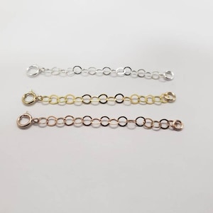 May include: Three silver, gold, and rose gold chain extenders with lobster clasps. Each extender is approximately 2 inches long.
