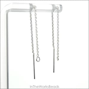 May include: Two silver chain earrings with a silver bar hanging from each chain. The earrings are displayed on a clear acrylic stand.
