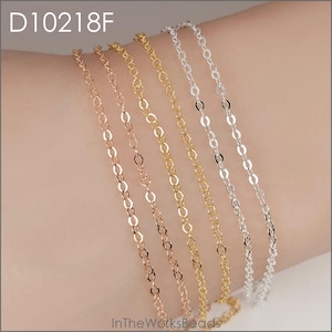 May include: Close-up of five delicate chain bracelets in gold, rose gold, and silver tones. The chains have a repeating oval link design. The image includes the text "D10218F" and "InTheWorksBeads".