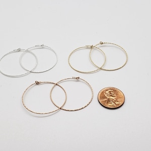 May include: Three pairs of hoop earrings in silver, gold, and rose gold. The earrings are all the same size and have a textured, twisted design. A penny is included for size reference.