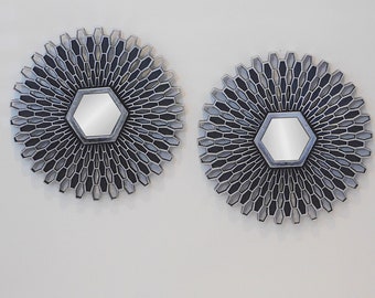 May include: Two silver-toned, round wall mirrors with a hexagonal design. Each mirror has a smaller hexagonal mirror in the center.