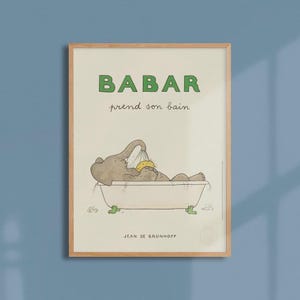 Puede incluir: Un póster enmarcado con Babar el elefante bañándose. La imagen muestra a Babar en una bañera, con el texto "BABAR prend son bain" en verde. El nombre del artista, Jean de Brunhoff, está en la parte inferior.