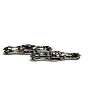 May include: Two silver-toned barrettes with filigree detailing and a rectangular purple gemstone in the center. The barrettes are displayed on a white background. These hair accessories are suitable for various hairstyles.