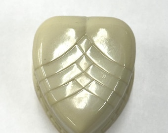 May include: A heart-shaped, off-white decorative box with a glossy finish. The box features a geometric design of intersecting lines and a slightly rounded top. The box is likely made of a hard plastic or resin material.