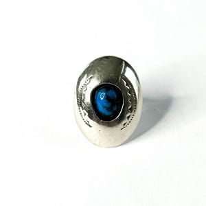 May include: A silver ring with a turquoise stone set in a decorative oval design.