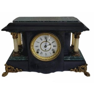 May include: A rectangular mantel clock featuring a black frame with green marble accents. The clock face is white with black Roman numerals and gold trim. It is supported by four ornate gold-toned feet and features four small columns with gold capitals.