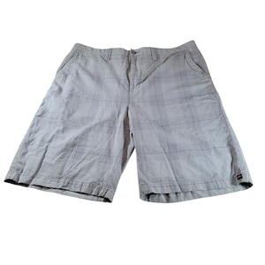May include: Light gray plaid shorts with a button and zipper closure. The shorts have two front pockets and two back pockets. The shorts are made of a lightweight fabric.