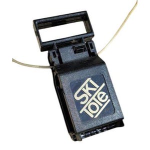 May include: Black ski tote with a rectangular handle and a square label that reads "SKI Tole" in white letters. A thin, silver-colored wire extends from the tote.