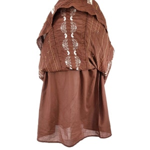 Peut inclure: Une tunique en coton marron avec des broderies blanches. La tunique a un col pliss&eacute; et une coupe ample et fluide.