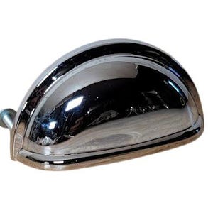 May include: A chrome-plated, semi-circular cabinet pull with a curved top and a flat bottom. The pull has a shiny, reflective surface and a bolt on the left side for mounting. The hardware is designed for use on drawers or cabinets.