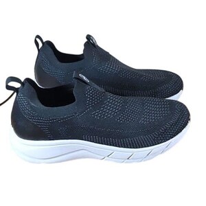 May include: Pair of black slip-on sneakers with a textured knit upper and white soles. The shoes have a pull tab at the heel for easy wear. The design is modern and suitable for casual wear.