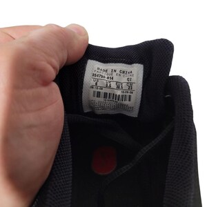 May include: Close-up of a black athletic shoe's interior, revealing a white label with text. The label indicates the shoe's size as US 6, UK 3.5, EUR 36.5, and CM 23. The shoe was made in China.